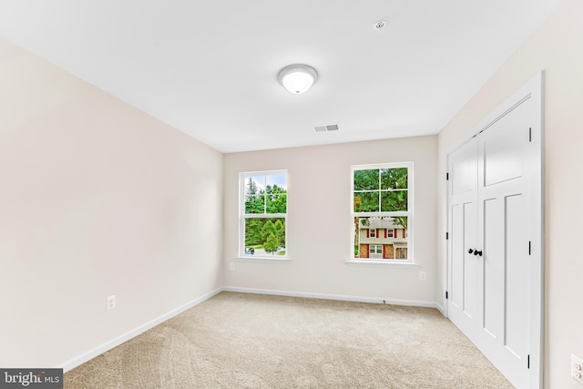 unfurnished bedroom with a closet and light colored carpet