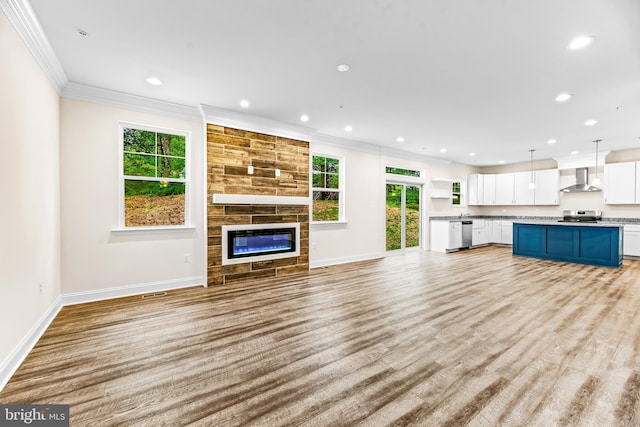 unfurnished living room featuring a tile fireplace, a wealth of natural light, crown molding, and light hardwood / wood-style floors