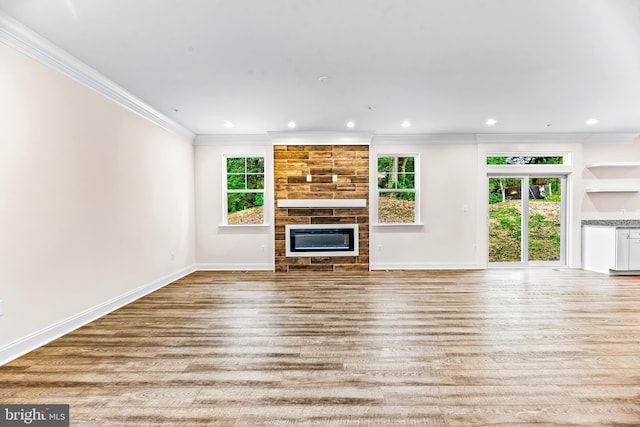 unfurnished living room with a large fireplace, ornamental molding, and light hardwood / wood-style flooring