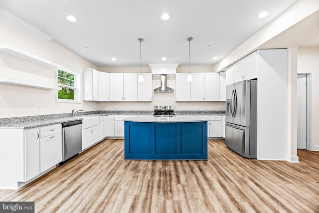 kitchen with appliances with stainless steel finishes, light wood-type flooring, wall chimney exhaust hood, decorative light fixtures, and white cabinetry