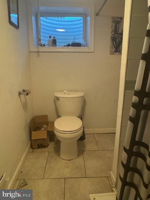 bathroom featuring toilet, tile patterned floors, and walk in shower