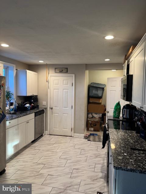 kitchen featuring dark stone countertops, sink, white cabinetry, and stainless steel appliances