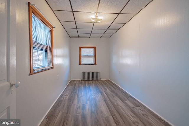 spare room with a paneled ceiling, radiator heating unit, and hardwood / wood-style floors