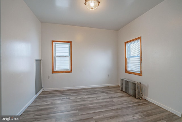 unfurnished room featuring light hardwood / wood-style floors and radiator heating unit