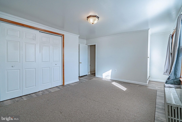 unfurnished bedroom featuring wood-type flooring, a closet, and ornamental molding