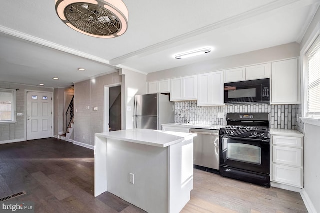 kitchen featuring black appliances, white cabinets, crown molding, decorative backsplash, and light hardwood / wood-style floors