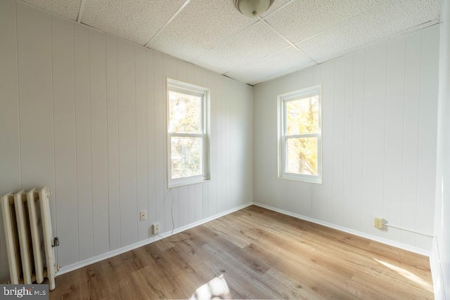 spare room with wood-type flooring, plenty of natural light, and radiator