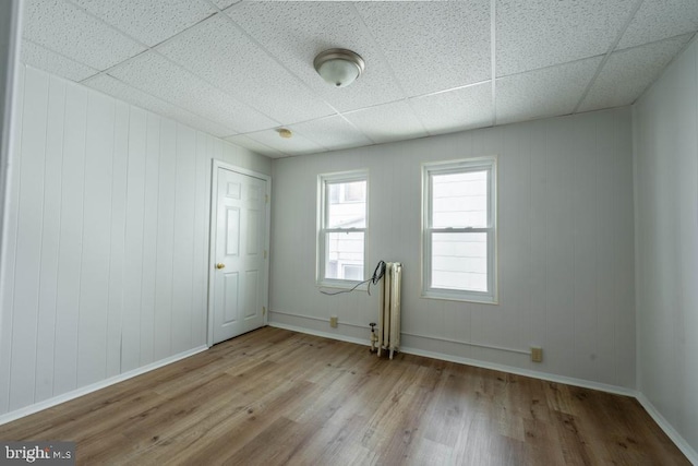 empty room featuring a paneled ceiling, light hardwood / wood-style floors, and radiator