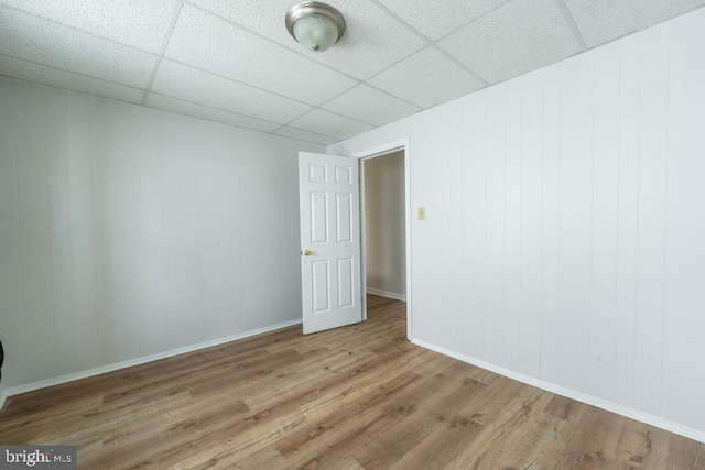 spare room with a drop ceiling and wood-type flooring