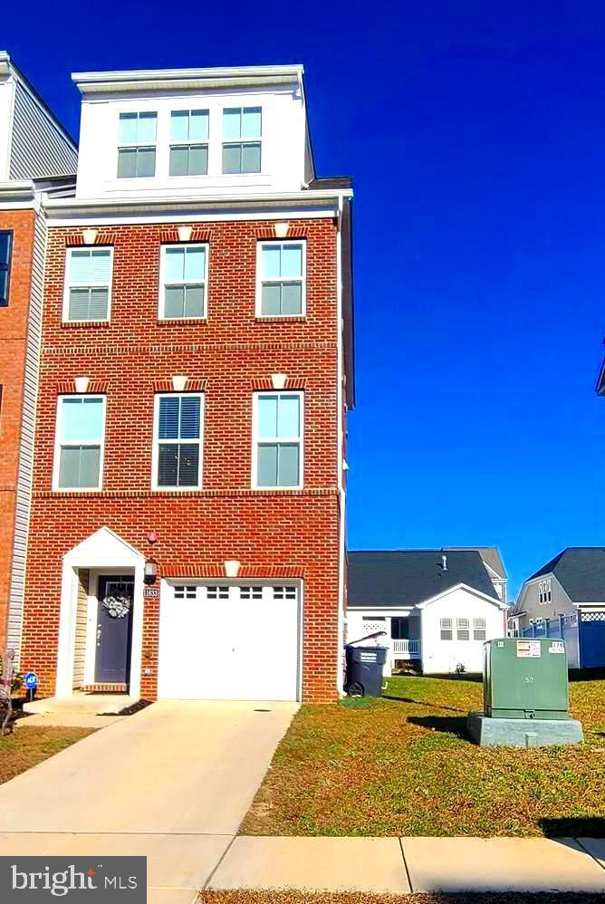 townhome / multi-family property featuring a garage and a front lawn