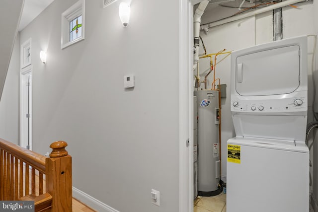 clothes washing area with stacked washer / dryer, electric water heater, and light tile patterned floors