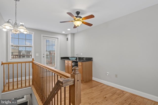 corridor featuring an inviting chandelier, light hardwood / wood-style flooring, and sink