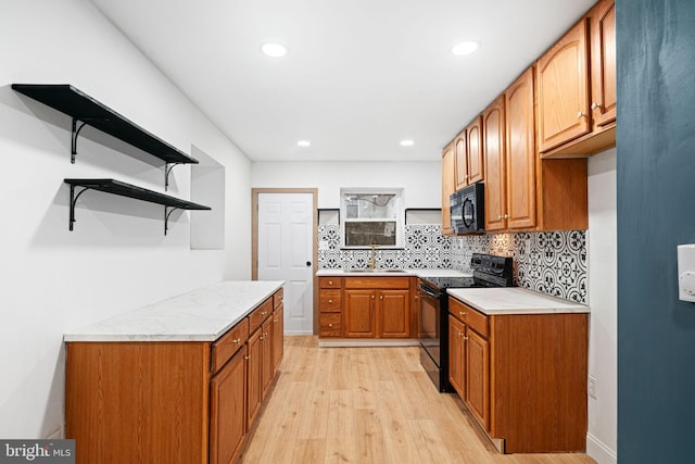 kitchen featuring sink, backsplash, light hardwood / wood-style flooring, and black appliances