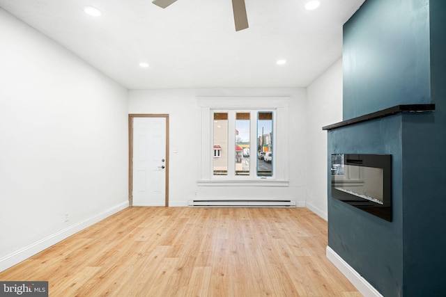 interior space with ceiling fan, a baseboard heating unit, and light wood-type flooring