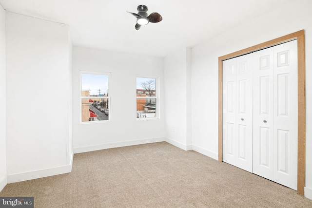 unfurnished bedroom with ceiling fan, light colored carpet, and a closet