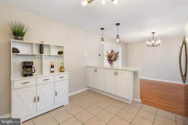 kitchen featuring kitchen peninsula, white cabinetry, light tile patterned flooring, and decorative light fixtures