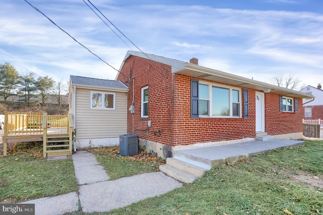 view of front of property with a front yard, cooling unit, and a wooden deck