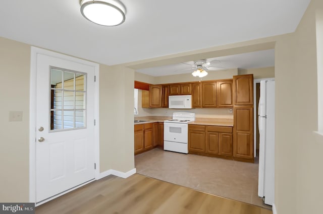 kitchen with white appliances, light hardwood / wood-style flooring, ceiling fan, and sink