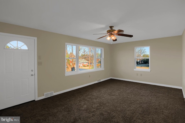 carpeted foyer featuring a wealth of natural light and ceiling fan