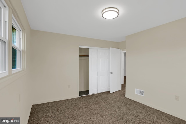 unfurnished bedroom featuring a closet and dark carpet