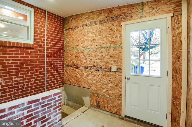 doorway to outside featuring brick wall