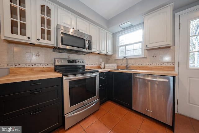 kitchen featuring white cabinets, sink, butcher block counters, and stainless steel appliances