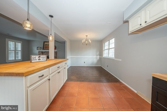 kitchen featuring wood counters, pendant lighting, an inviting chandelier, white cabinets, and light tile patterned flooring