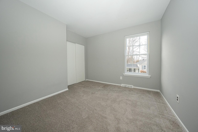 unfurnished bedroom featuring light carpet and a closet