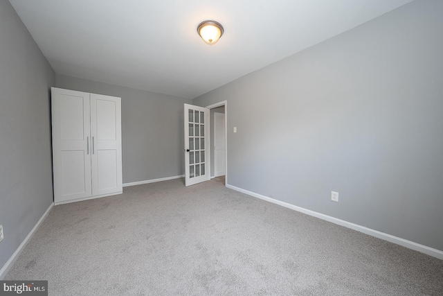 carpeted spare room featuring french doors