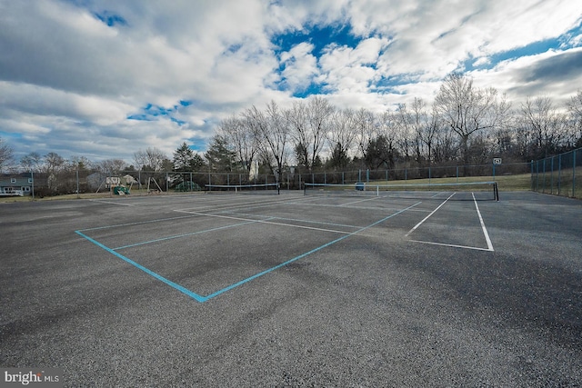 view of tennis court with a playground