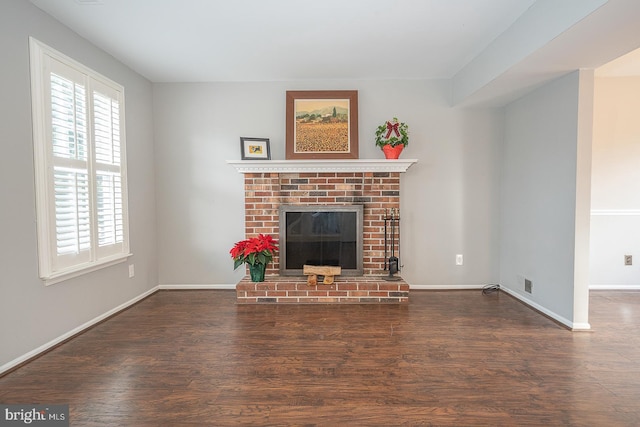 unfurnished living room featuring dark hardwood / wood-style floors and a brick fireplace