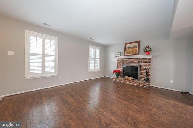 unfurnished living room with dark wood-type flooring and a brick fireplace