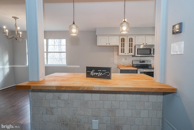 kitchen with pendant lighting, white cabinetry, butcher block counters, and stainless steel appliances