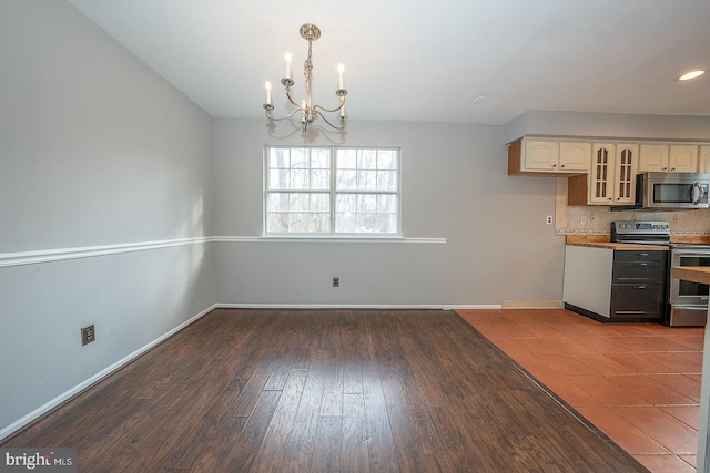 kitchen with appliances with stainless steel finishes, wood-type flooring, decorative light fixtures, a notable chandelier, and white cabinetry