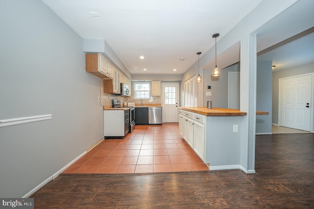 kitchen featuring hardwood / wood-style floors, wooden counters, sink, hanging light fixtures, and appliances with stainless steel finishes