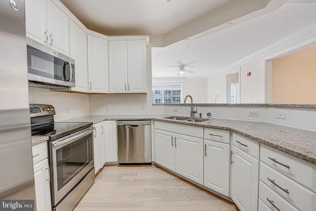 kitchen featuring white cabinets, stainless steel appliances, light hardwood / wood-style floors, sink, and light stone counters