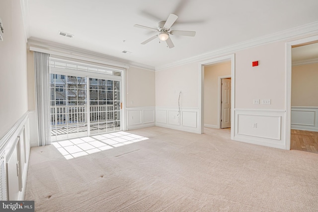 spare room featuring ceiling fan, crown molding, and light carpet