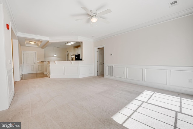 unfurnished living room with ceiling fan, light colored carpet, and crown molding