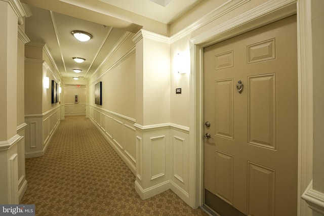 hallway with ornamental molding and dark colored carpet