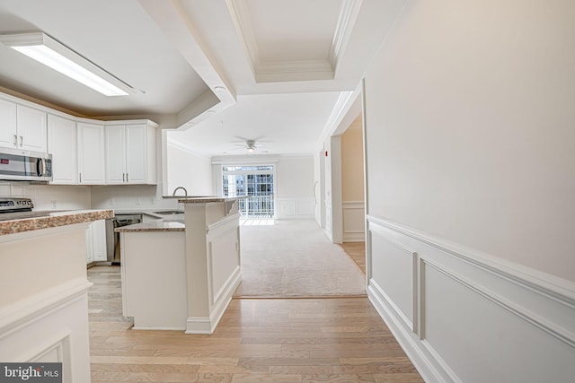 kitchen featuring white cabinets, stainless steel appliances, sink, kitchen peninsula, and light stone counters