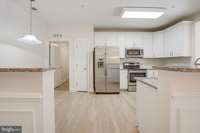 kitchen with decorative light fixtures, backsplash, white cabinets, light wood-type flooring, and stainless steel appliances