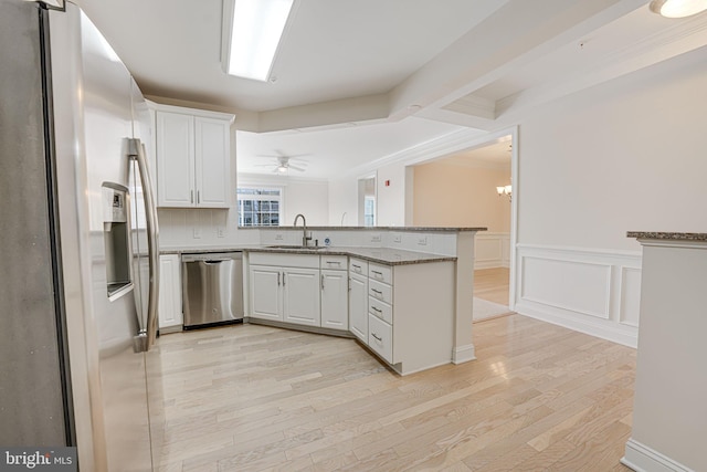 kitchen featuring white cabinets, stainless steel appliances, kitchen peninsula, and sink