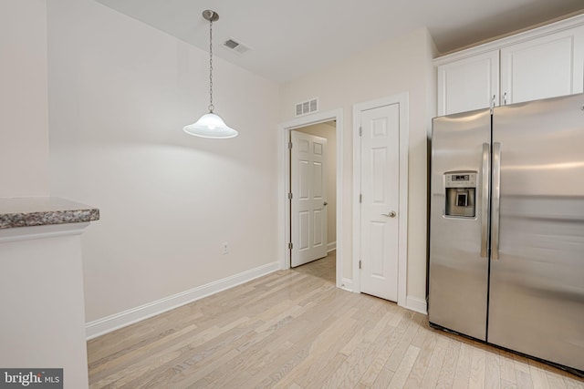 kitchen with light stone countertops, decorative light fixtures, white cabinetry, stainless steel fridge with ice dispenser, and light hardwood / wood-style flooring