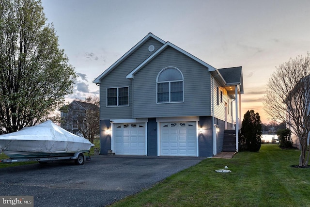 property exterior at dusk with a garage and a lawn