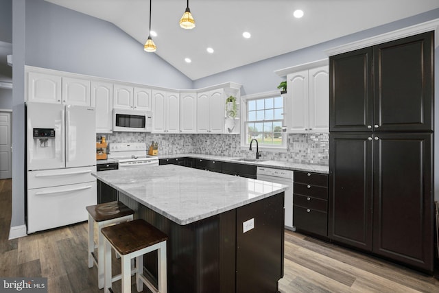 kitchen with white appliances, vaulted ceiling, sink, light hardwood / wood-style flooring, and a kitchen island