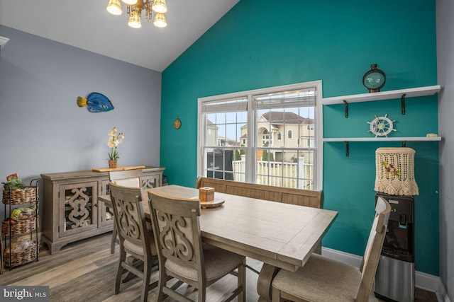 dining room with hardwood / wood-style floors, high vaulted ceiling, and an inviting chandelier