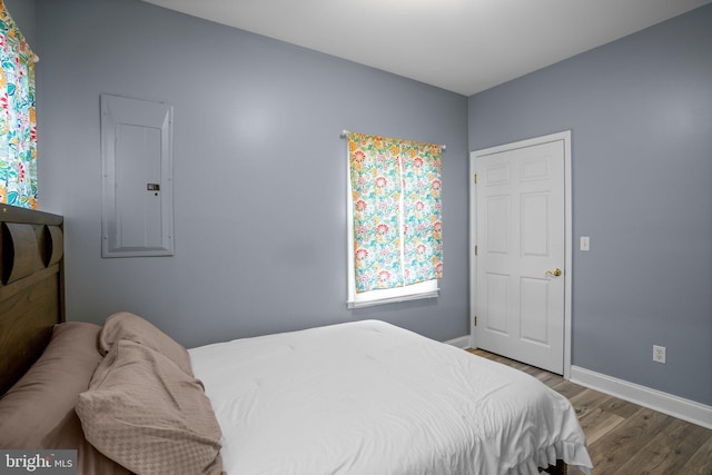 bedroom with electric panel and hardwood / wood-style floors