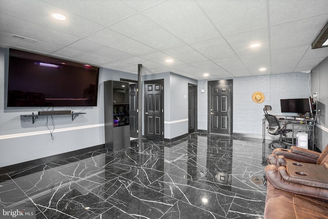 living room with a drop ceiling and brick wall