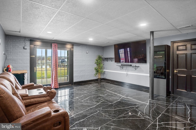 living room with a paneled ceiling and brick wall