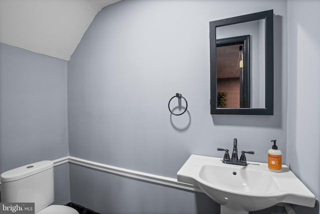 bathroom featuring vaulted ceiling, toilet, and sink